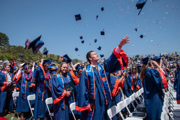 students tossing grad caps amidst confetti