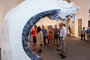 People look at a piece of art in the shape of a big wave - Pepperdine University