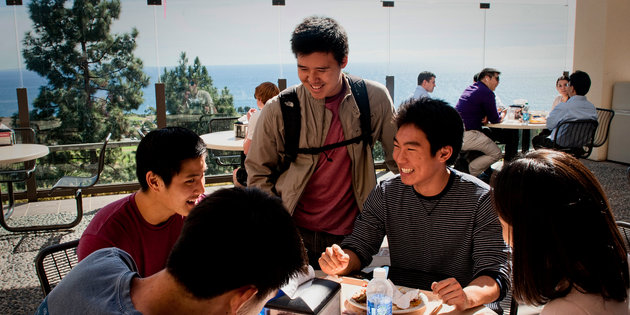 A group of Asian male students laugh together at Waves Cafe - Pepperdine University