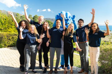 Pepperdine students waving with Willie the Wave mascot