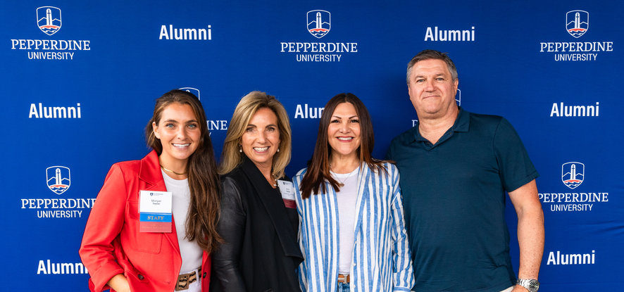 alumni in front of Pepperdine banner