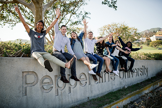 group of students waving from pepperdine sign