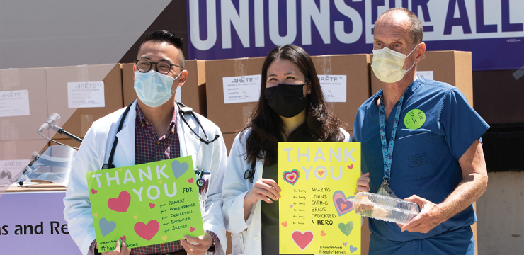 Medical professionals holding signs with encouraging messages on them.