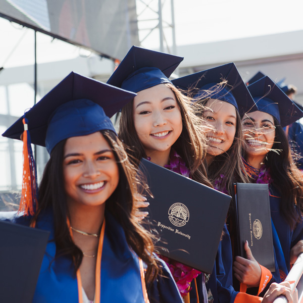 Four women smiling in caps and gowns