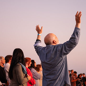 man worshipping with hands in air among the crowd