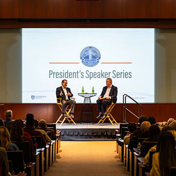 two people on stage and crowd looking on