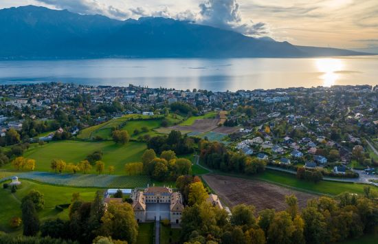 Chateau aerial view with the sun setting on Lake Geneva in the back