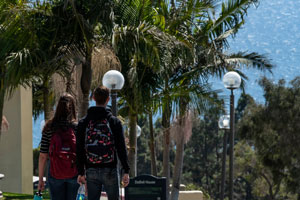 Students walking on campus with a view of the ocean