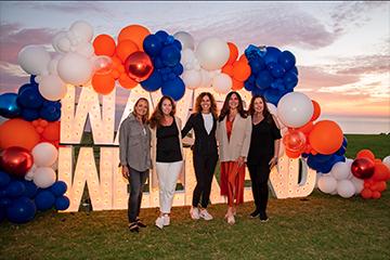reunion attendees standing with balloons at Waves Weekend lighted sign