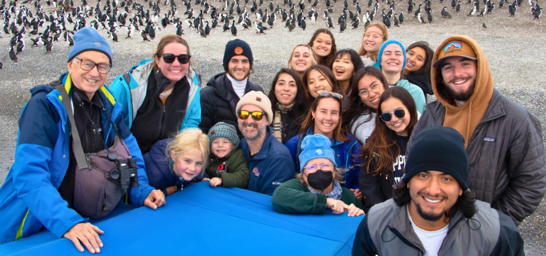 Penguins stand behind a group of students.