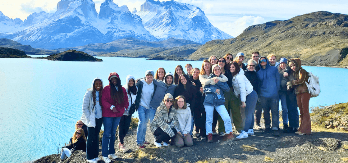 A group of students stand in front of giant icebergs.