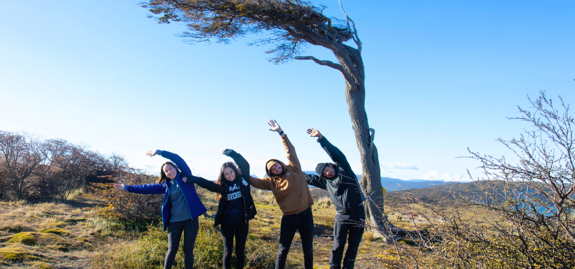Four students lean with tree in Ushuaia, Argentina.
