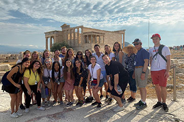 Group of students poses for a photo in front of ancient ruins