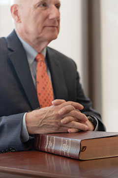 Marrs sits with hands folded over Bible