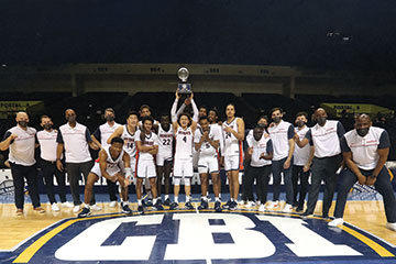 Men's basketball team holding up championship trophy.