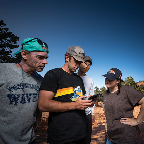 Terry Benedict, Paul Kim, and students looking at video footage on a camera