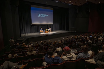 An auditorium of people listening