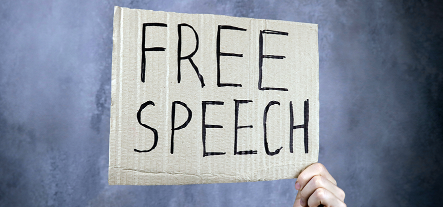 Hand holds up sign that reads 'free speech'