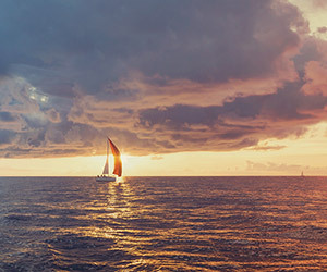Harbor promotional image showing a lone sailboat sailing on the horizon at sunset