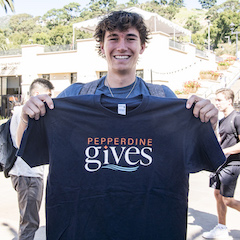 Student holding a Pepperdine Gives t-shirt