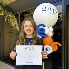 Student holding a Pepperdine Gives t-shirt
