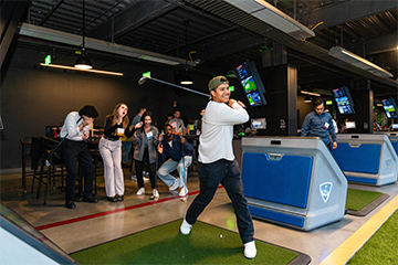 Alumni playing golf at Topgolf event