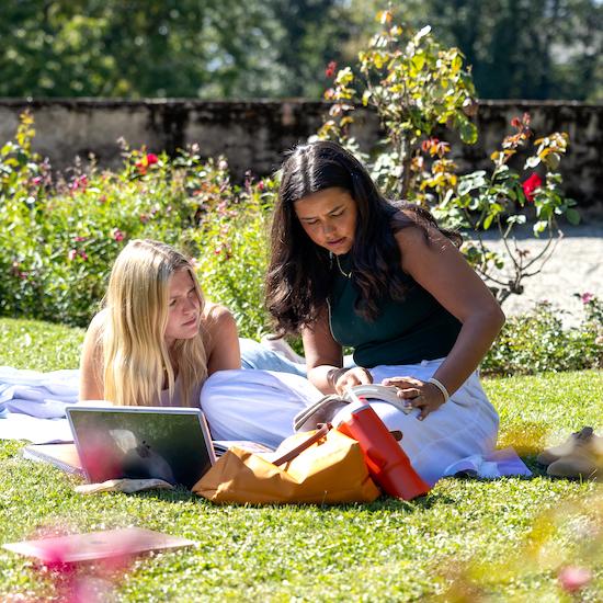 Students studying outside on the grass at the Chateau d'Hauteville in Switzerland.