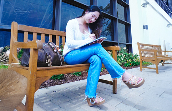 woman writing on a paper sitting on a bench