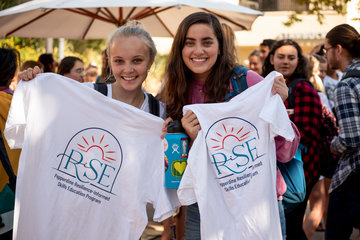 Students holding a RISE t-shirt