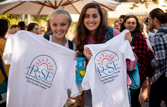 Students holding a RISE t-shirt