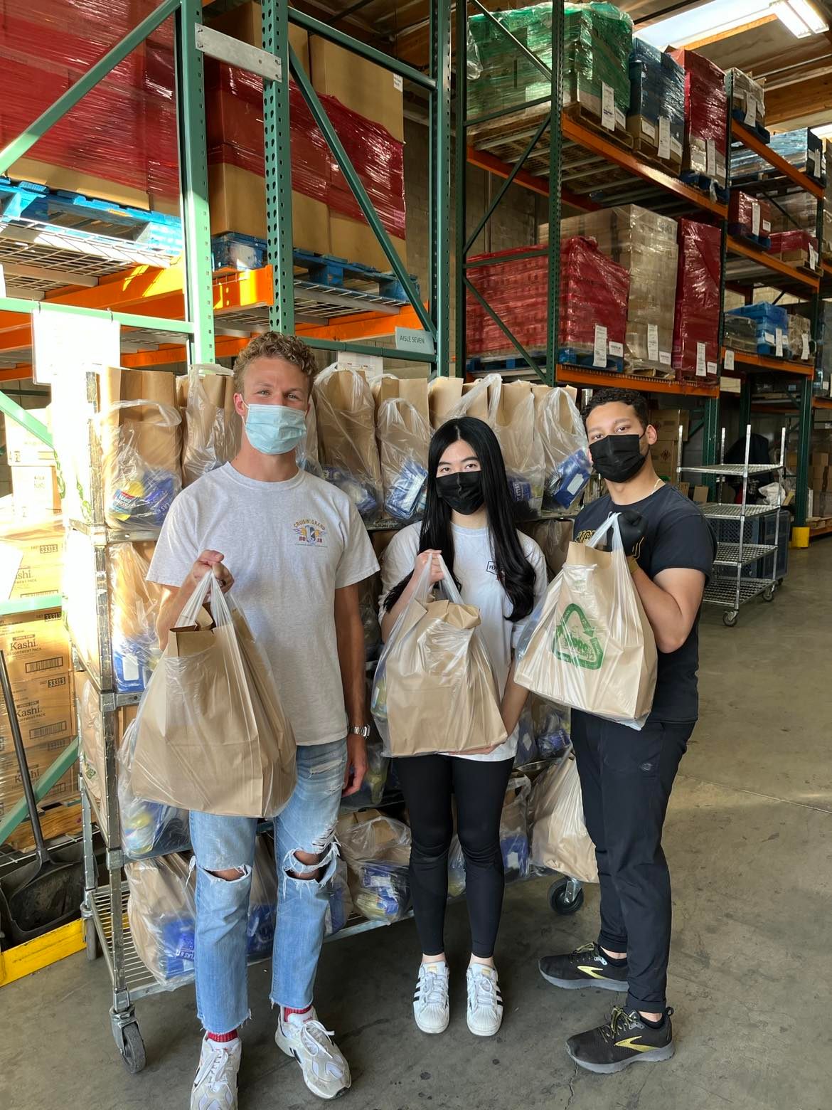 Three student volunteers posing with food bags
