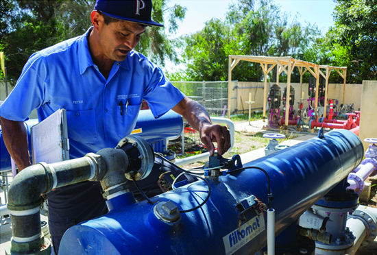 Man wearing Pepperdine Baseball hat working on irrigation monitoring pipes