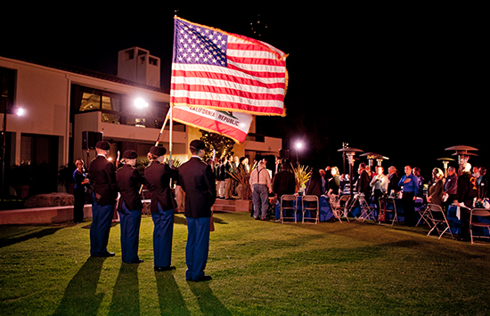 Four veterans holding flags outside on lawn at evening event