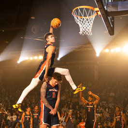 Student slam dunking over another student